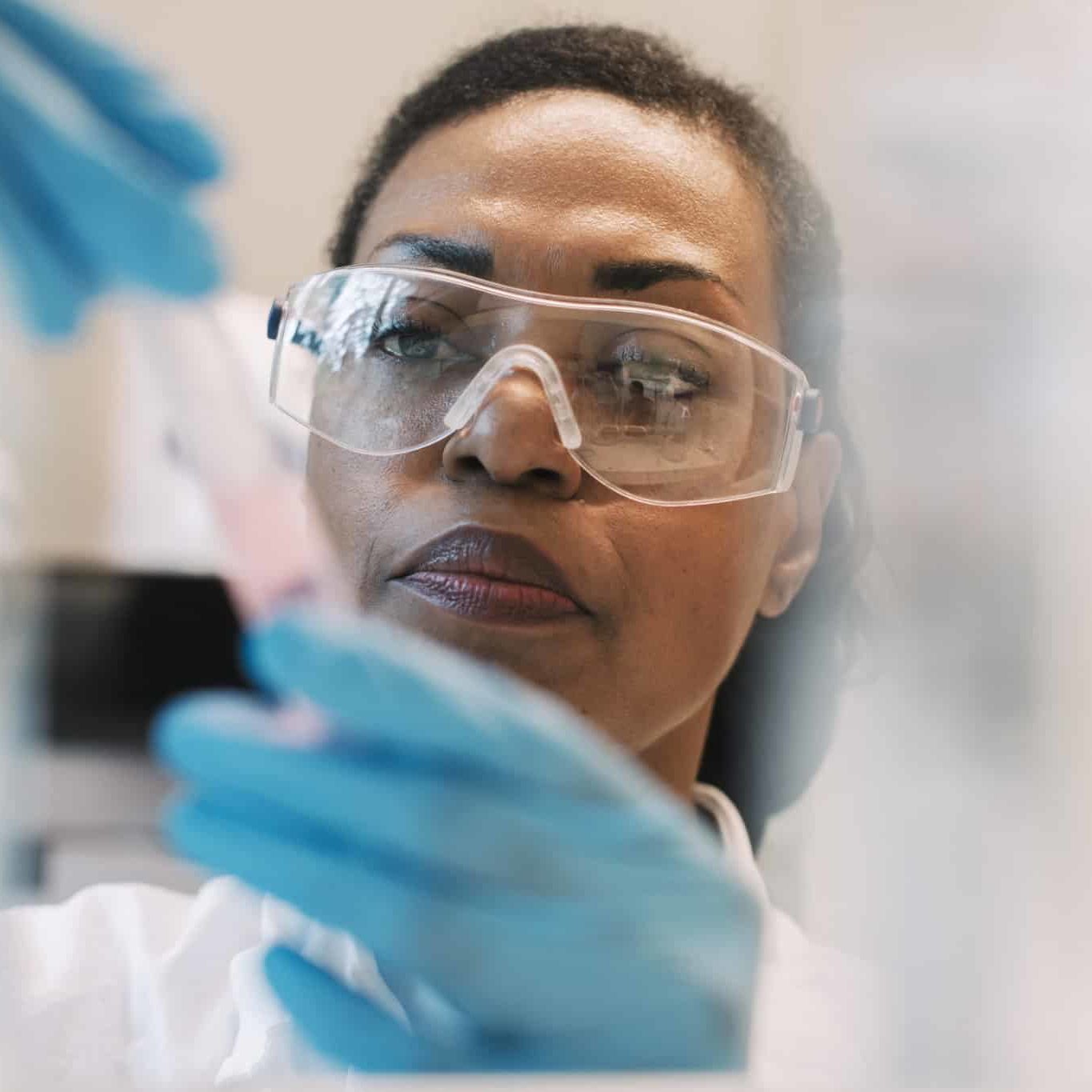 Mature Female Virologist Wearing Eyeglasses Experimenting In Laboratory